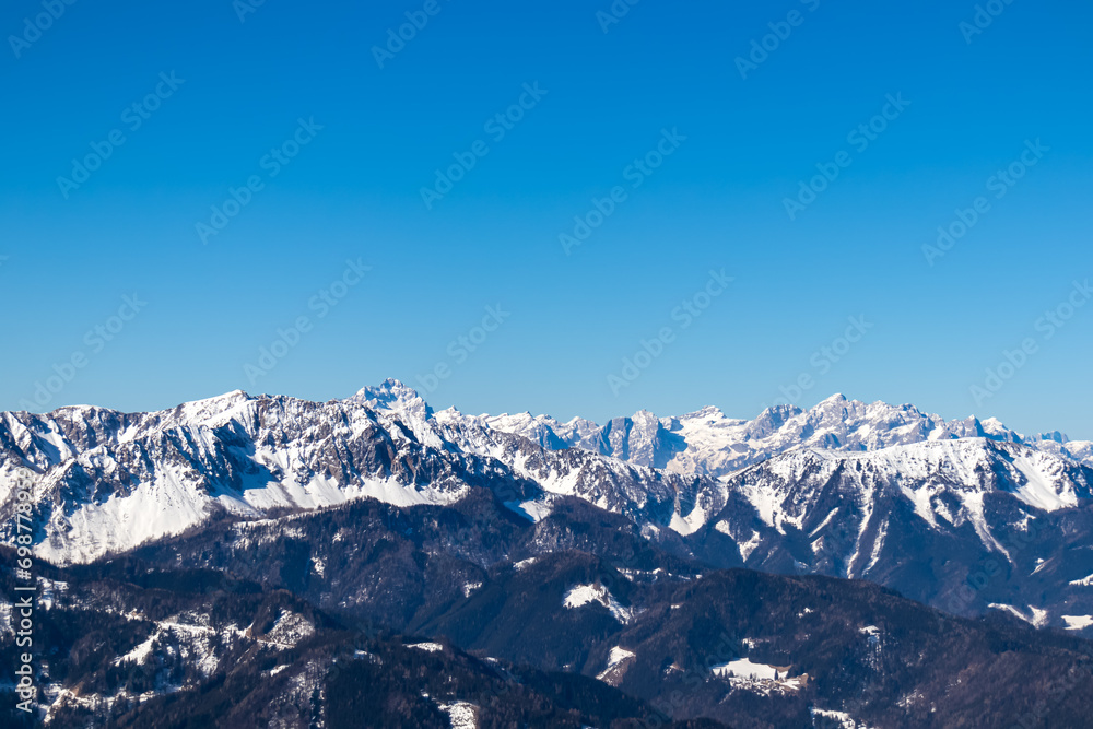 Scenic view on snow capped mountain peaks of Karawanks, Julian and Kamnik Savinja Alps in Carinthia (Kaernten), Austria. Winter wonderland in Austrian Alps, Europe. Aerial view from Ferlacher Horn