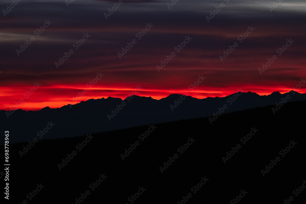 Dark red sky at Italian Dolomites with mountain peaks in distance. Twillight hour at Italian Alps.
