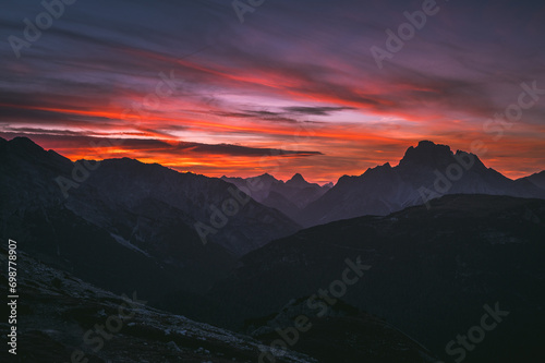 Dark red sky at Italian Dolomites with mountain peaks in distance. Twillight hour at Italian Alps. 