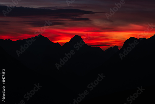 Obraz na płótnie Dark red sky at Italian Dolomites with mountain peaks in distance. Twillight hour at Italian Alps. w salonie
