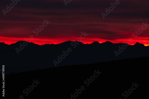 Obraz na płótnie Dark red sky at Italian Dolomites with mountain peaks in distance. Twillight hour at Italian Alps. w salonie