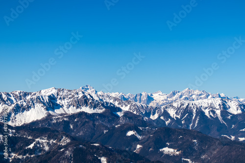 Scenic view on snow capped mountain peaks of Karawanks, Julian and Kamnik Savinja Alps in Carinthia (Kaernten), Austria. Winter wonderland in Austrian Alps, Europe. Aerial view from Ferlacher Horn