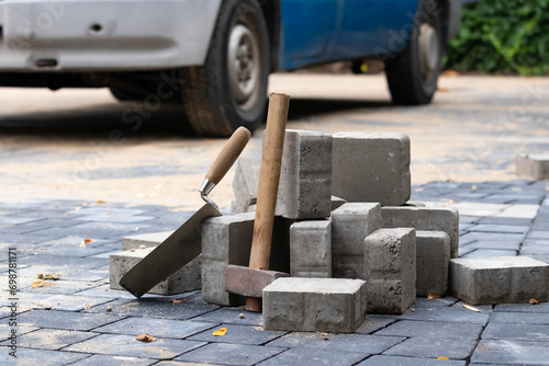 Hammer and trowel on the sidewalk with concrete bricks.