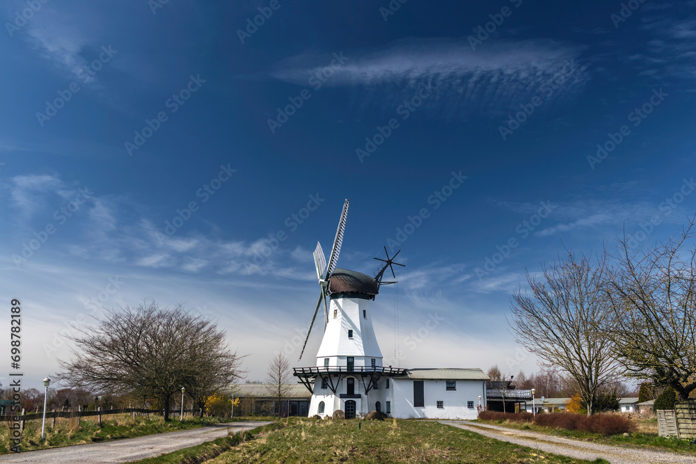 Stock rural landscape with Dutch style classic white windmill and blue sky in Holland