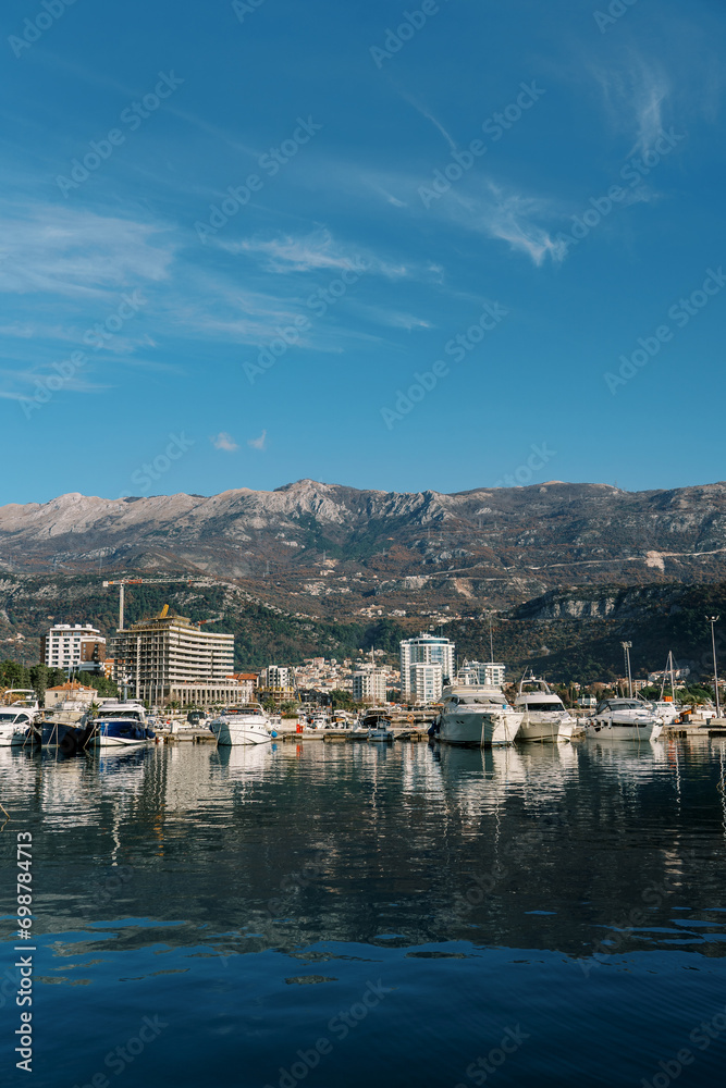 Yachts moored off the coast with high-rise buildings at the foot of the mountains