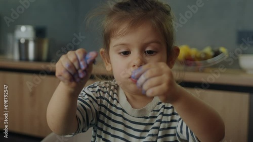 Little girl showing her palms dirty with blue plasticine to the camera. Daycare. Creative kids molding at home. photo