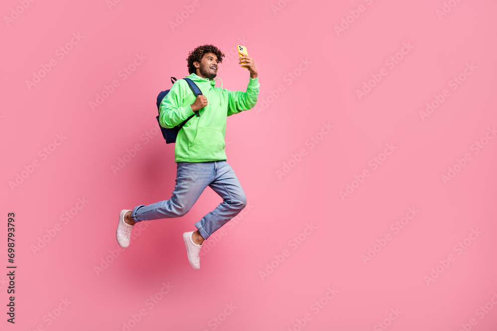 Full body photo of influencer blogger beginner young student indian guy using smartphone wear backpack isolated on pink color background