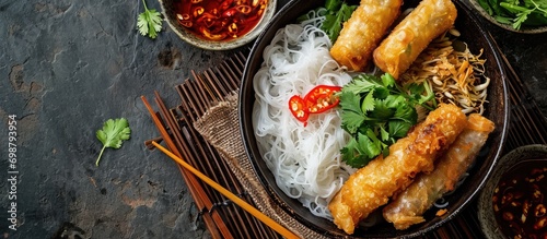 Top view of Asian food: Cold rice vermicelli with sauce, paired with fried spring rolls in a bowl. photo