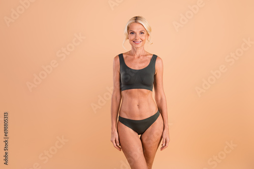 Photo of pensioner woman blonde hair posing new gray lingerie model slender body figure healthcare app ad isolated on beige color background