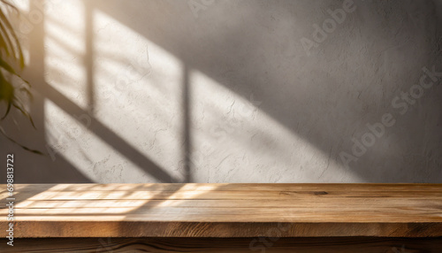 Empty wooden table top near stucco wall with with sunlight falling from the window and shadows. Table top with copy space for product advertising