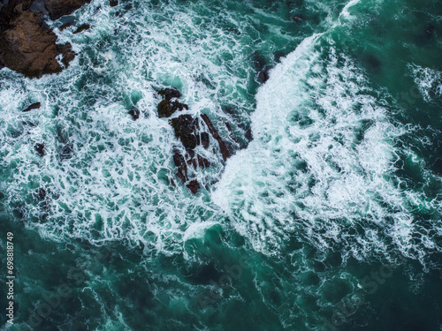 Aerial view of the huge Pacific ocean waves hitting the shore of California.