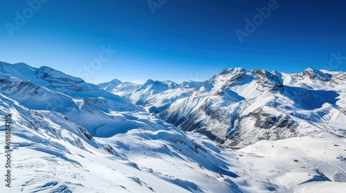 Panoramic view of a snowy mountain range under a clear blue sky. © Bijac