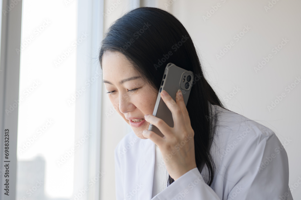 スマホで謝罪する白衣女性 スマホで謝罪する白衣女性