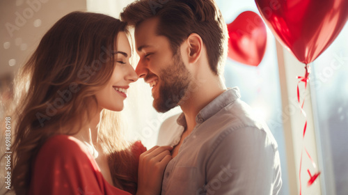 A smiling couple in a romantic embrace with red heart balloons in the background.