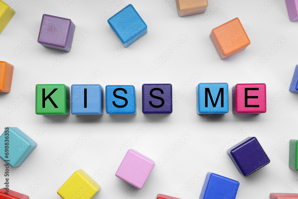 Obraz premium Colorful cubes with phrase Kiss Me on white background, flat lay