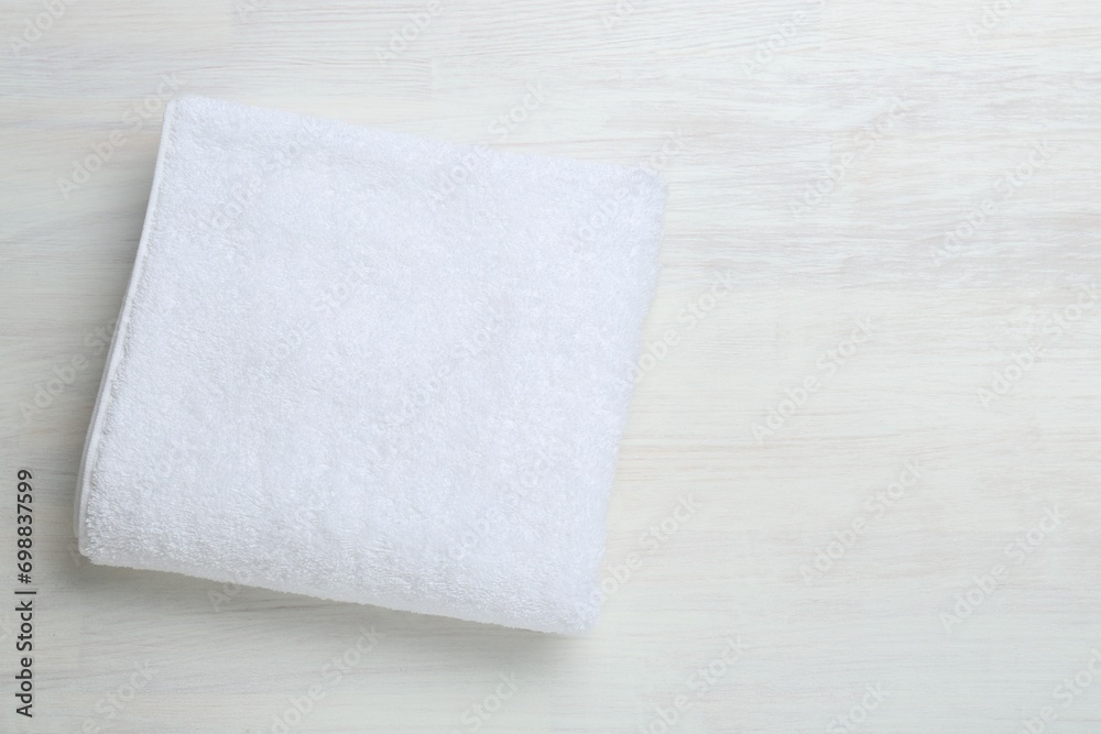 White terry towel on light wooden table, top view. Space for text White terry towel on light wooden table, top view. Space for text