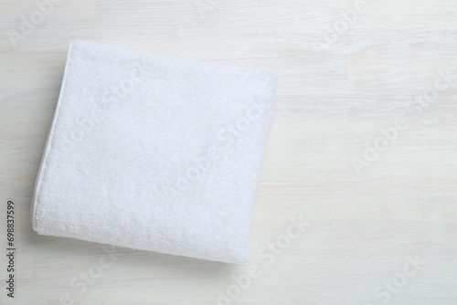 White terry towel on light wooden table, top view. Space for text