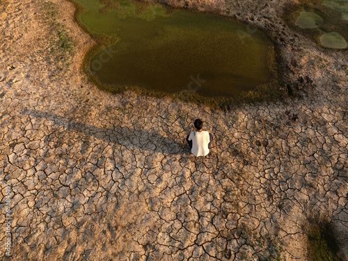 Man sitting near drying river metaphor water crisis, drought and climate change photo