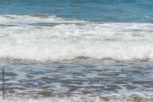 Top view of the foam of a wave arriving at the seashore.