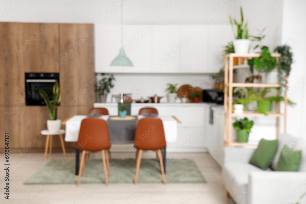 Blurred view of kitchen with green plants, dining table and counters