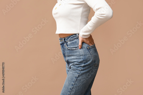 Beautiful young Asian woman in stylish jeans on brown background, closeup