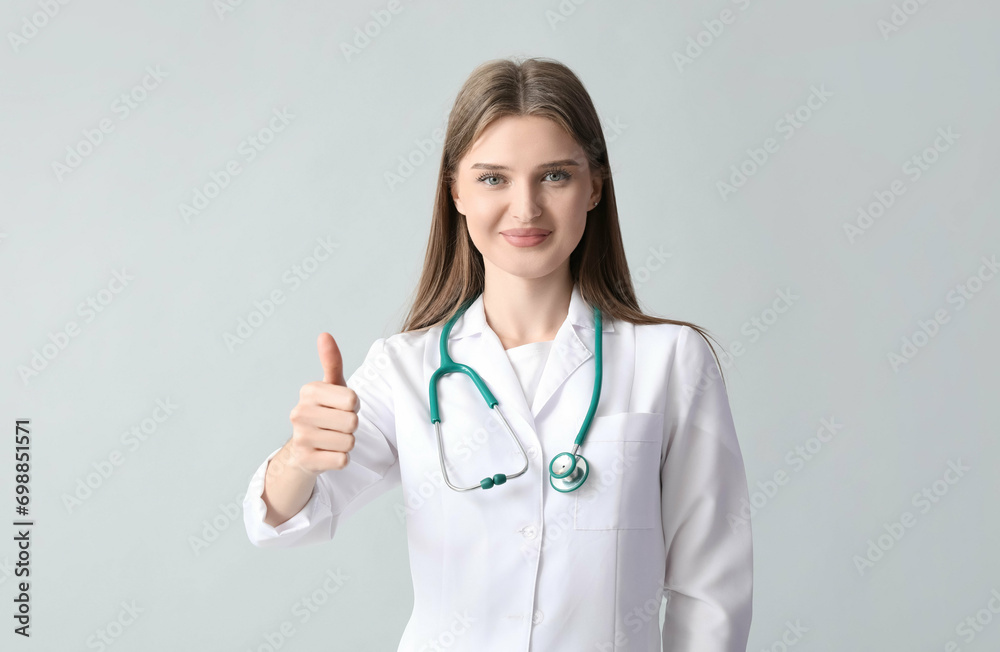 Beautiful doctor showing thumb-up on light background Beautiful doctor showing thumb-up on light background