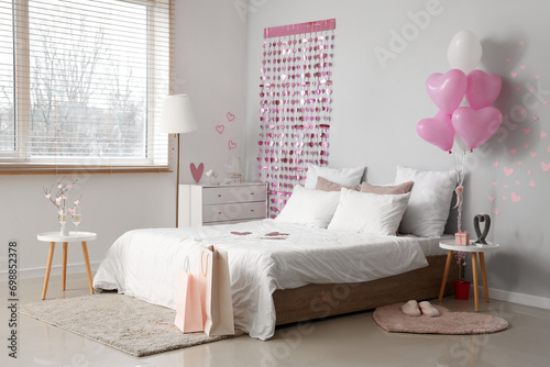 Interior of light bedroom with cozy bed and heart-shaped balloons. Valentine's Day celebration