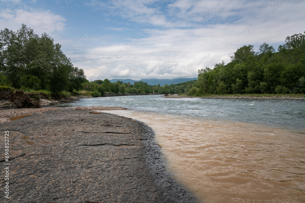 View of the Belaya River and the Caucasus Mountains in the background on a sunny summer day with clouds, Dakhovskaya, Republic of Adygea, Russia