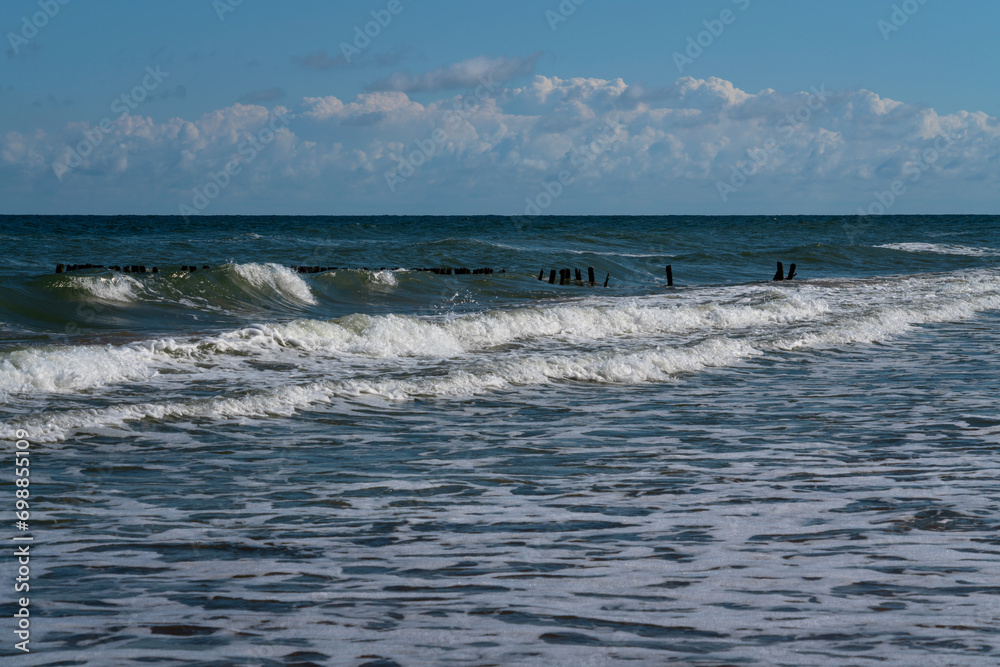 View of the Baltic Sea and wooden breakwaters on the Curonian Spit beach on a sunny summer day, Kaliningrad region, Russia View of the Baltic Sea and wooden breakwaters on the Curonian Spit beach on a sunny summer day, Kaliningrad region, Russia