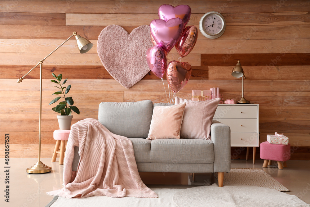 Interior of festive living room with grey sofa and heart-shaped balloons. Valentine's Day celebration - obrazy, fototapety, plakaty 
