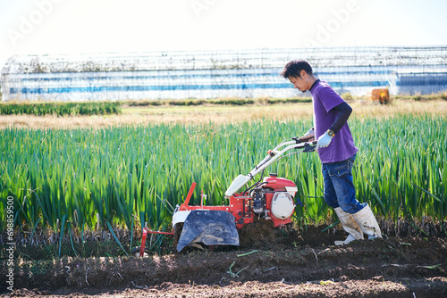 ネギの収穫のために耕運機で畑を耕す日本人男性 photo