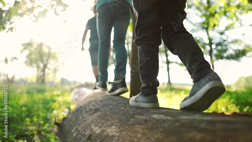 baby boy group playing in the forest park. close-up child feet walking on a fallen tree log. happy family kid dream concept. a child group in sneakers lifestyle walks on a fallen tree in park photo
