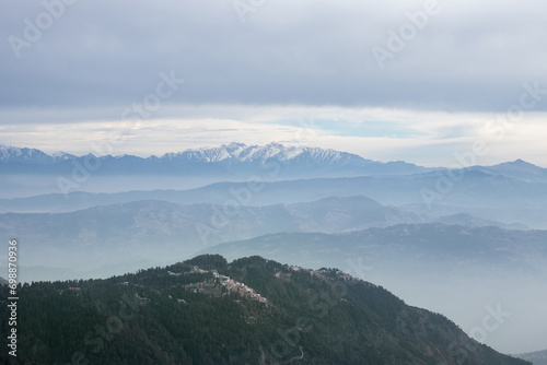 Clouds over snow covered mountains with trees