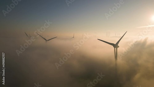 Cinematic aerial view of wind turbines in the misty sky at sunrise photo