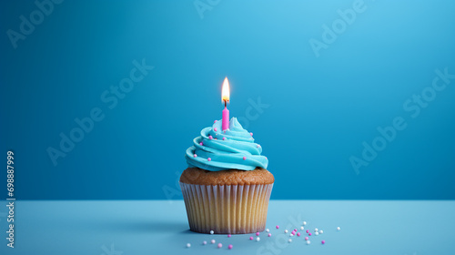 birthday cupcake with one candle on blue background and sprinkles photo