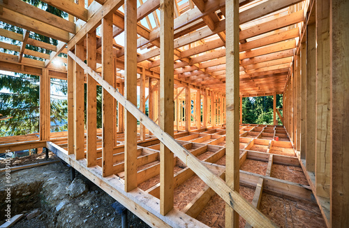 Under-construction residential wooden frame home located near a forest. Commencement of a new construction project for a cozy house or a mountain cottage. Idea of contemporary ecological construction. © anatoliy_gleb