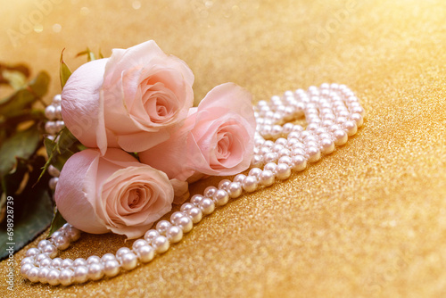 Pink rose and pearl necklace on a shiny gold background 