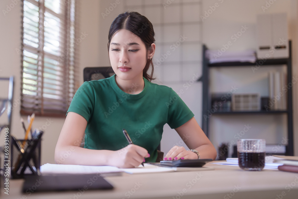 Young asian student women use calculator with finance to writing notes in notebook and doing homework after studying lecture webinar in online class and learning knowledge remote education from home Young asian student women use calculator with finance to writing notes in notebook and doing homework after studying lecture webinar in online class and learning knowledge remote education from home