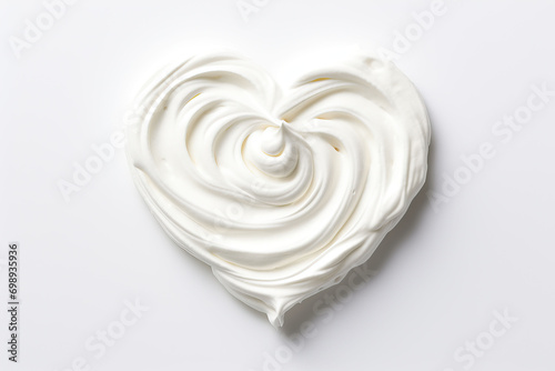 White whipped cream in the shape of a heart on a white background. photo