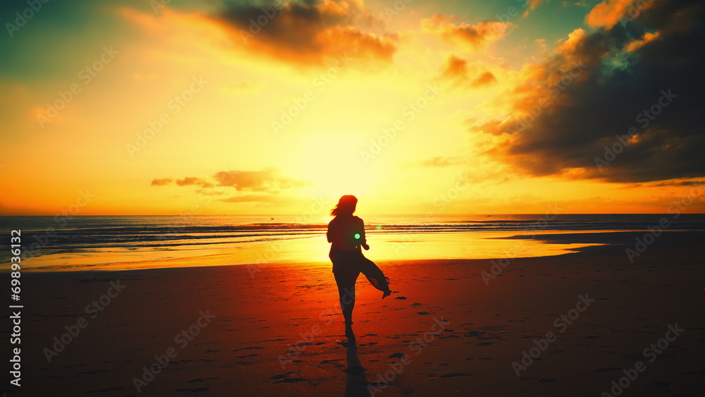Silhouette of a sexy slender woman running along the waves towards the sun at an orange sunset near the seashore, walking along the warm ocean water at an orange summer sunset. Slow motion in 4K
