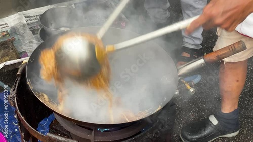 Street food vendor cooks a stir fry noodle dish using a wok pan at Chulia street, George Town, Penang, Malaysia. photo