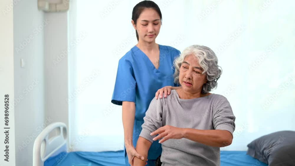 Asian physiotherapist helping elderly woman patient stretching arm in hand during training hand with patient Back problems in bed Asian physiotherapist helping elderly woman patient stretching arm in hand during training hand with patient Back problems in bed