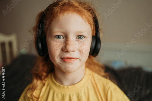 Smiling girl listening to music through wireless headphone at home photo