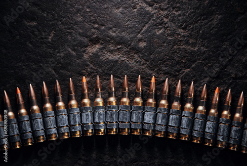 Machine gun bullet belt on the floor. Background on the military theme. Ammo, chain of ammo on concrete background. Top view of machine gun belt cartridge 7.62 mm caliber on dark background photo