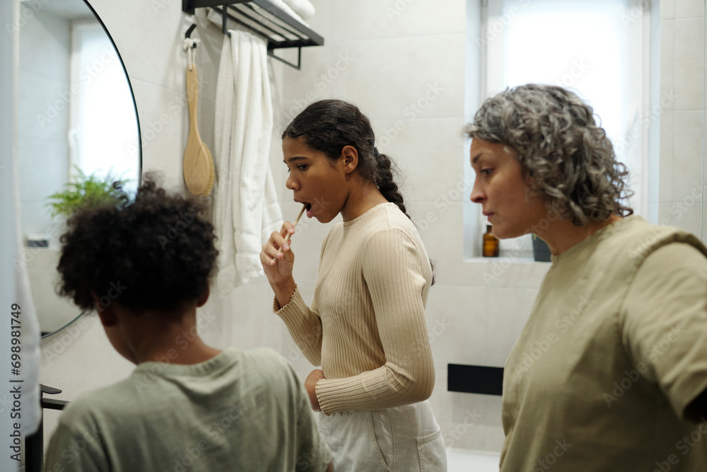 Mother looking at children brushing teeth in morning Mother looking at children brushing teeth in morning