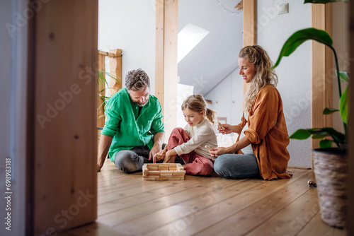 Parents playing block game with daughter in corridor at home photo
