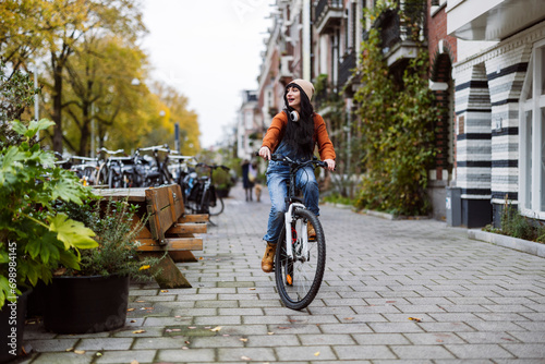 Happy woman riding bicycle on footpath near buildings photo