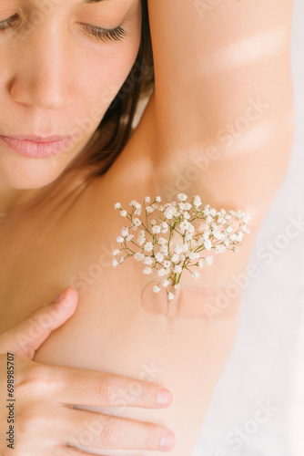 Woman with flowers on armpit against white background photo