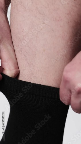 A man pulls and adjusts the elastic band on black socks