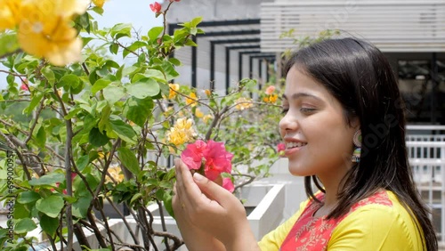 A young Indian woman smells Bougainvillaea flowers - beautiful smile  stress-relief  mental health  scent. Asian girl relaxing and connecting with nature - spiritual healing  mood booster  emotiona... photo